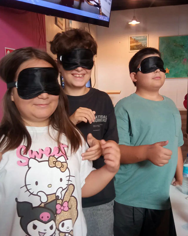 Una niña y dos niños participando de una actividad.